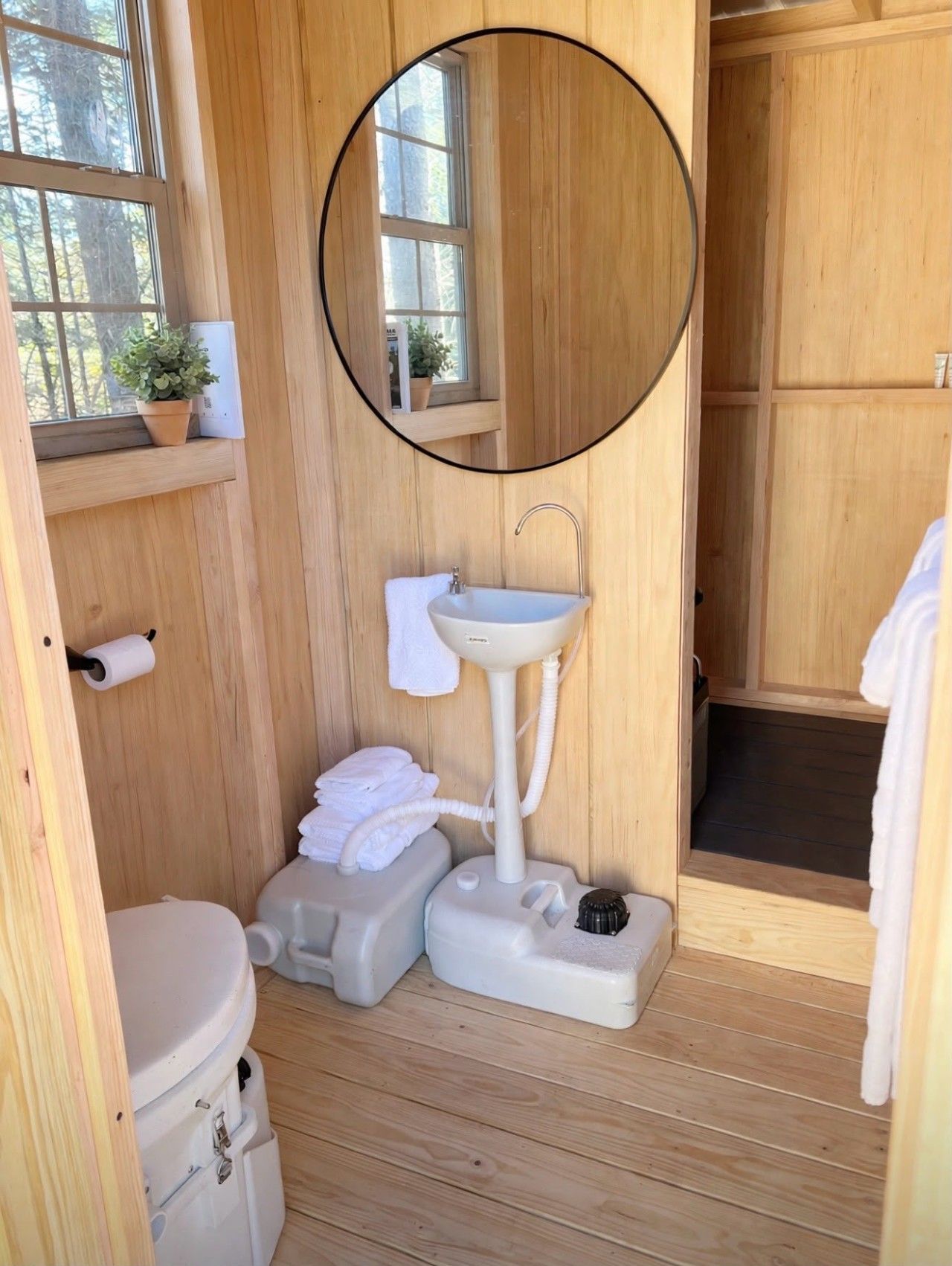 Een kleine houten badkamer met toilet, wastafel en douche.