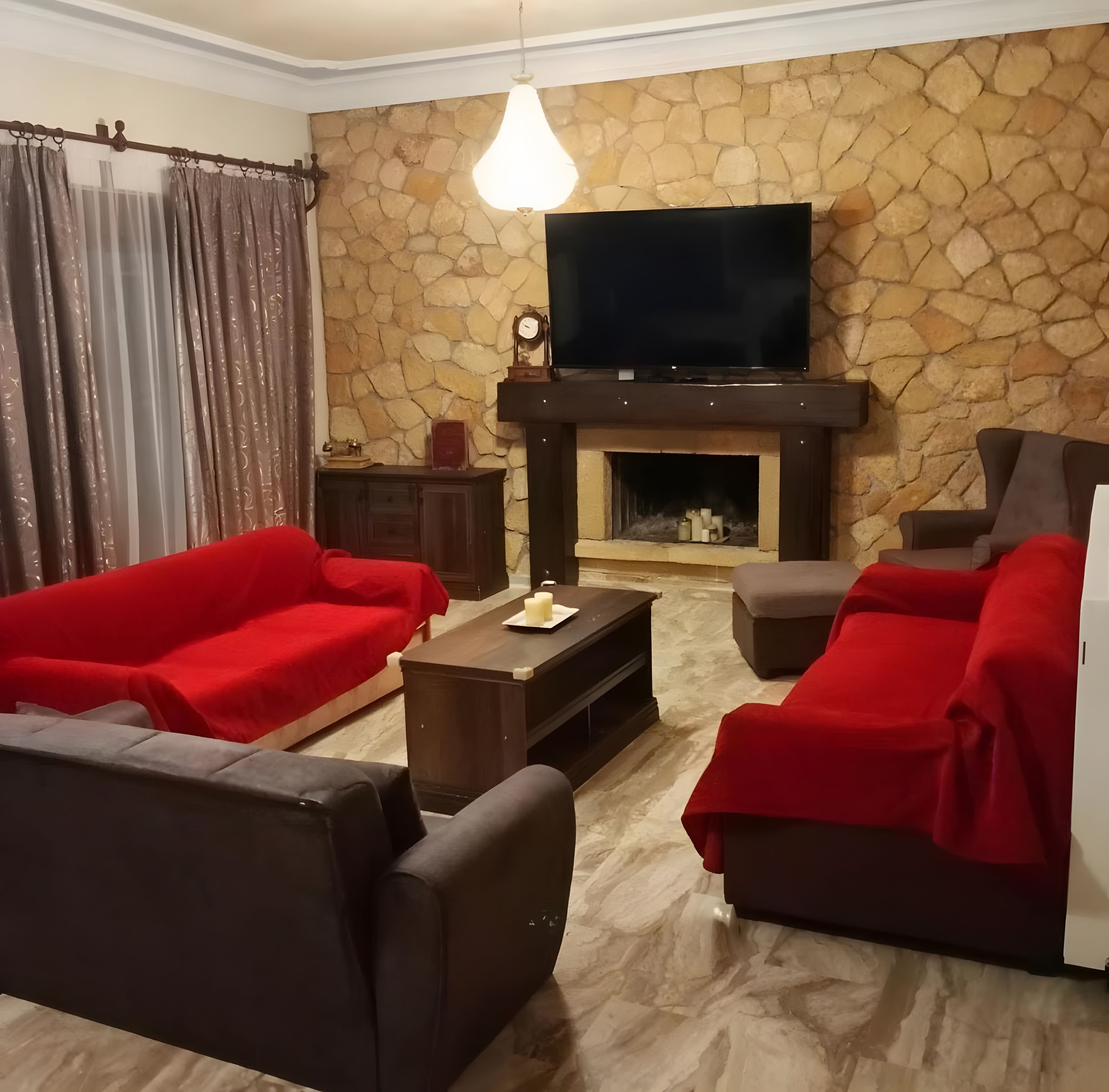 Ein Wohnzimmer mit Steinwand, Kamin und Flachbildfernseher.