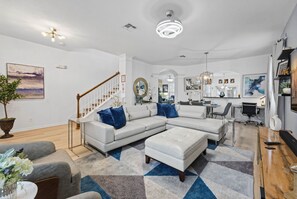A modern living room with a sectional sofa, a dining area, and a kitchen. - 6BR Windsor Hills Home Near Disney With Pool (Kissimmee)