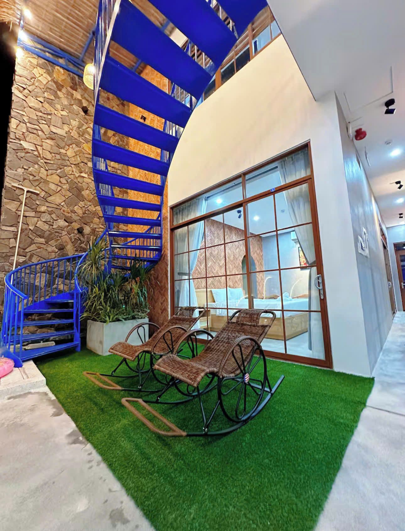 A modern interior with a spiral staircase, a seating area with wicker furniture, and a stone wall.