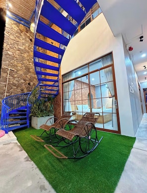 Ein modernes Interieur mit einer Wendeltreppe, einer Sitzecke mit Korbmöbeln und einer Steinwand.