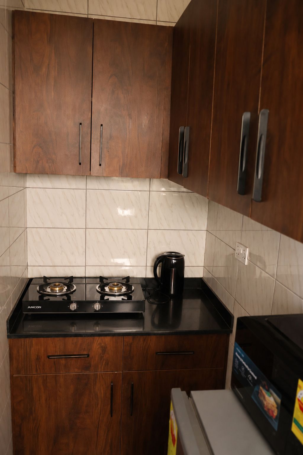 Una cocina con armarios de madera, encimera negra y cocina a gas.