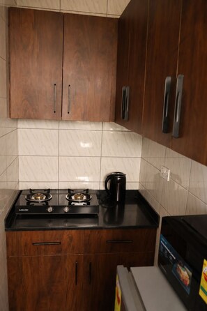 Een keuken met houten kastjes, een zwart aanrecht en een gasfornuis.