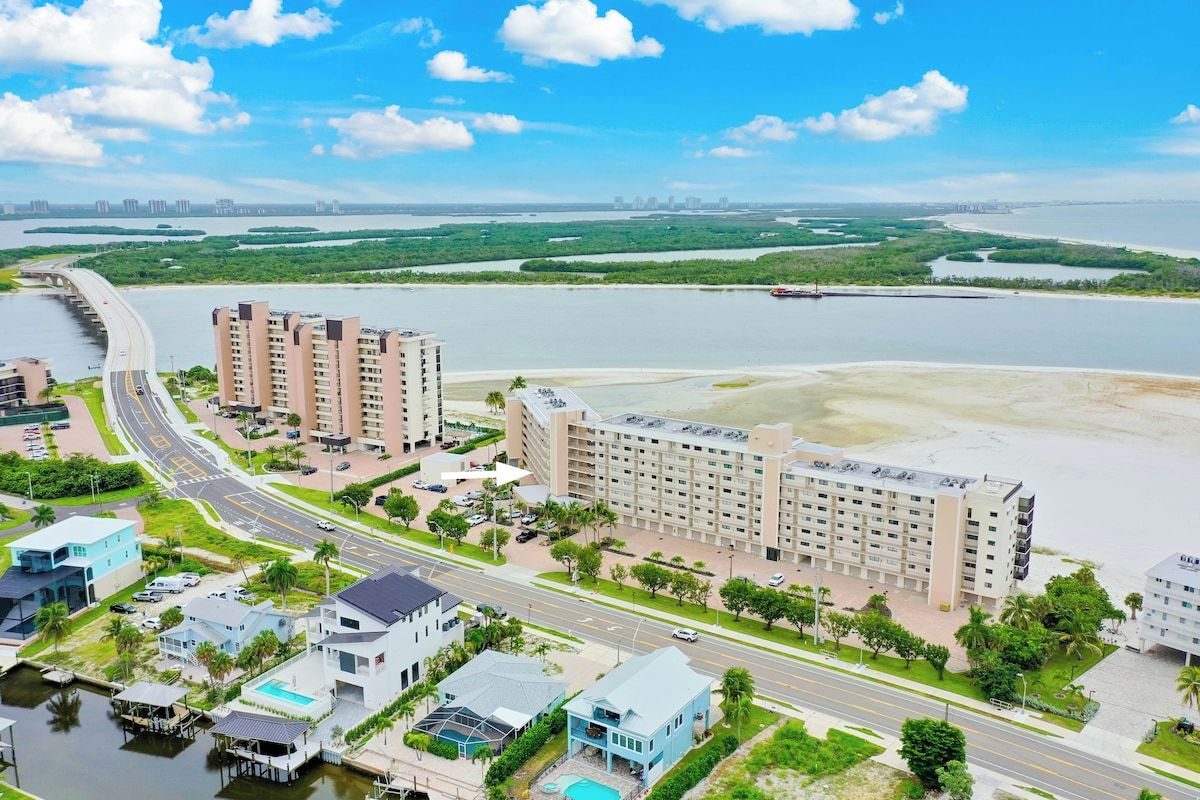 A coastal hotel with multiple buildings, a marina, and a beach.