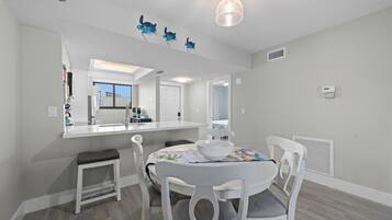A modern kitchen with white cabinetry, a central island with seating, and a pendant light.