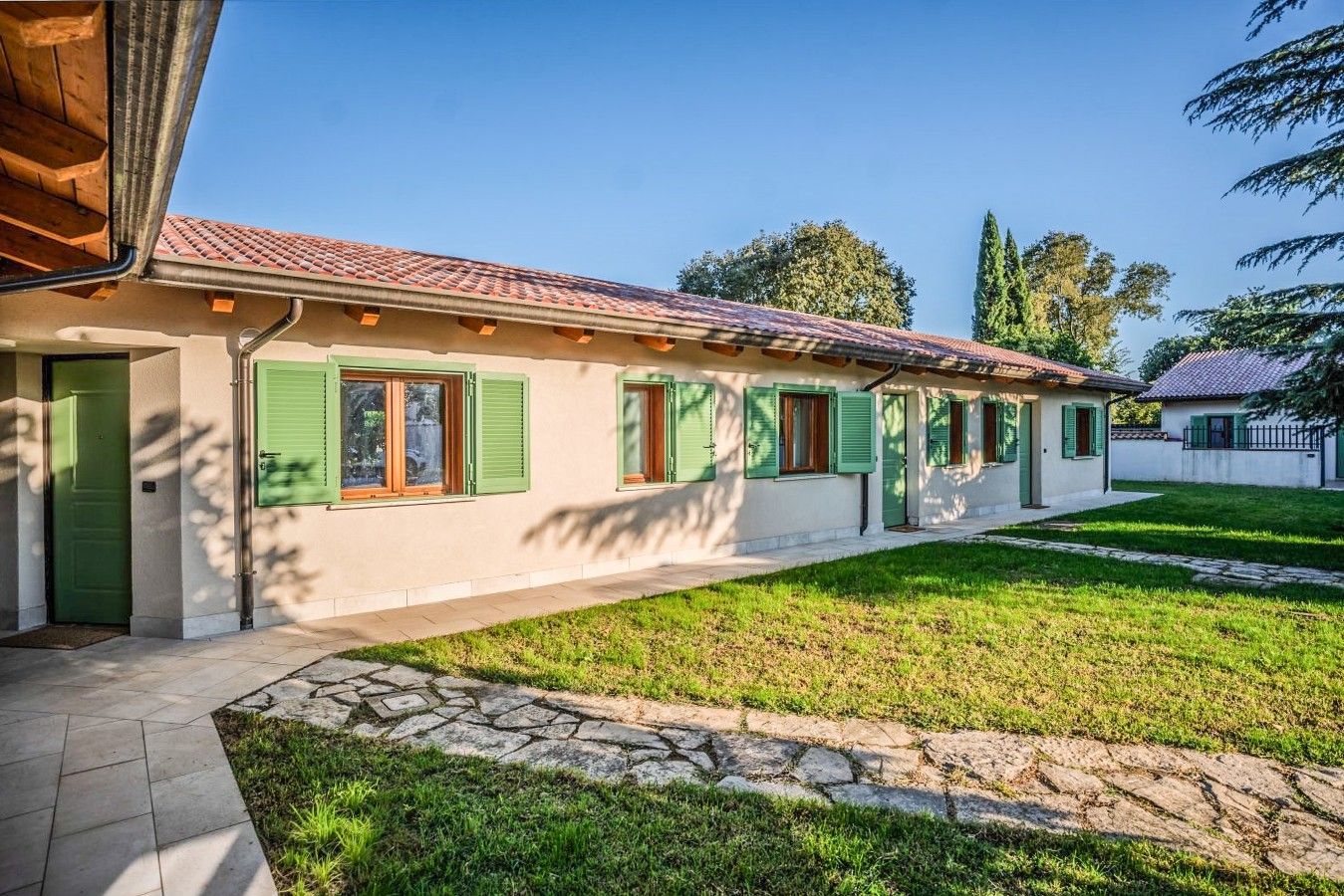 A row of houses with green shutters and a stone pathway leading to the entrance.