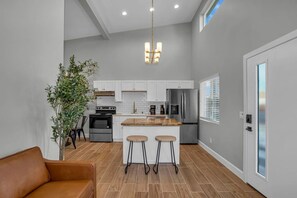 A modern kitchen with white cabinets, stainless steel appliances, and a wooden island with bar stools. - Near Legoland & Beaches | Prime Vista Monthly Stay (Vista)