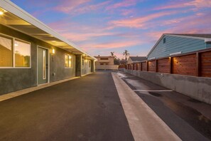 A long, narrow parking area with a building on the left and a wooden fence on the right. - Near Legoland & Beaches | Prime Vista Monthly Stay (Vista)