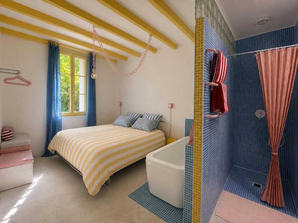 Una camera da letto con un letto, una vasca da bagno bianca e un angolo doccia con tenda.