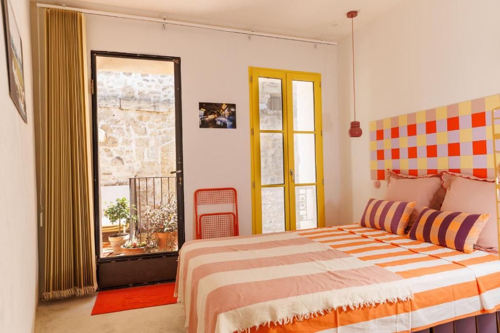 A bedroom with a bed, a window, a door, and a wall-mounted light fixture.