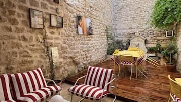 Un'area salotto all'aperto coperta, con mobili a righe, un tavolo e una sedia gialla.
