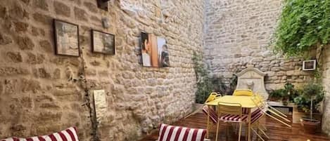 A covered outdoor seating area with striped furniture, a table, and a yellow chair.