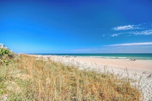 A beach with a clear sky, a sandy shore, and a building in the background. - Cape Coddages 205 · Oceanfront 2BR Surfside Beach (Surfside Beach)