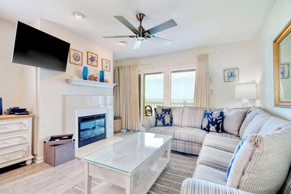 A living room with a fireplace, a sofa, a coffee table, and a television. - Cape Coddages 205 · Oceanfront 2BR Surfside Beach (Surfside Beach)
