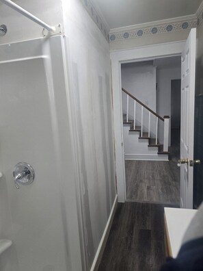 A hallway with a door on the left, a staircase in the center, and a dark wooden floor. - Welcoming 7-bedroom house with AC in charming Salisbury (Salisbury)