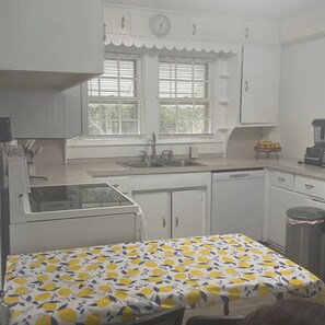 A kitchen with white cabinets, a sink, a stove, and a window with blinds. - Welcoming 7-bedroom house with AC in charming Salisbury (Salisbury)