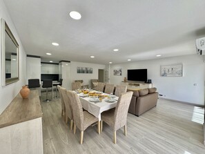 Ein modernes Wohnzimmer mit Essbereich, einem Flachbildfernseher und einer Couch.