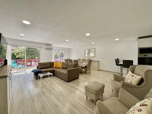 A spacious living area with a sofa, ottoman, and dining table. - Vilamoura Marina Beach 2 by Homing (Loulé)