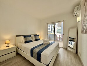 A hotel room with a bed, bedside table, lamp, and a view of the outside. - Vilamoura Marina Beach 2 by Homing (Loulé)