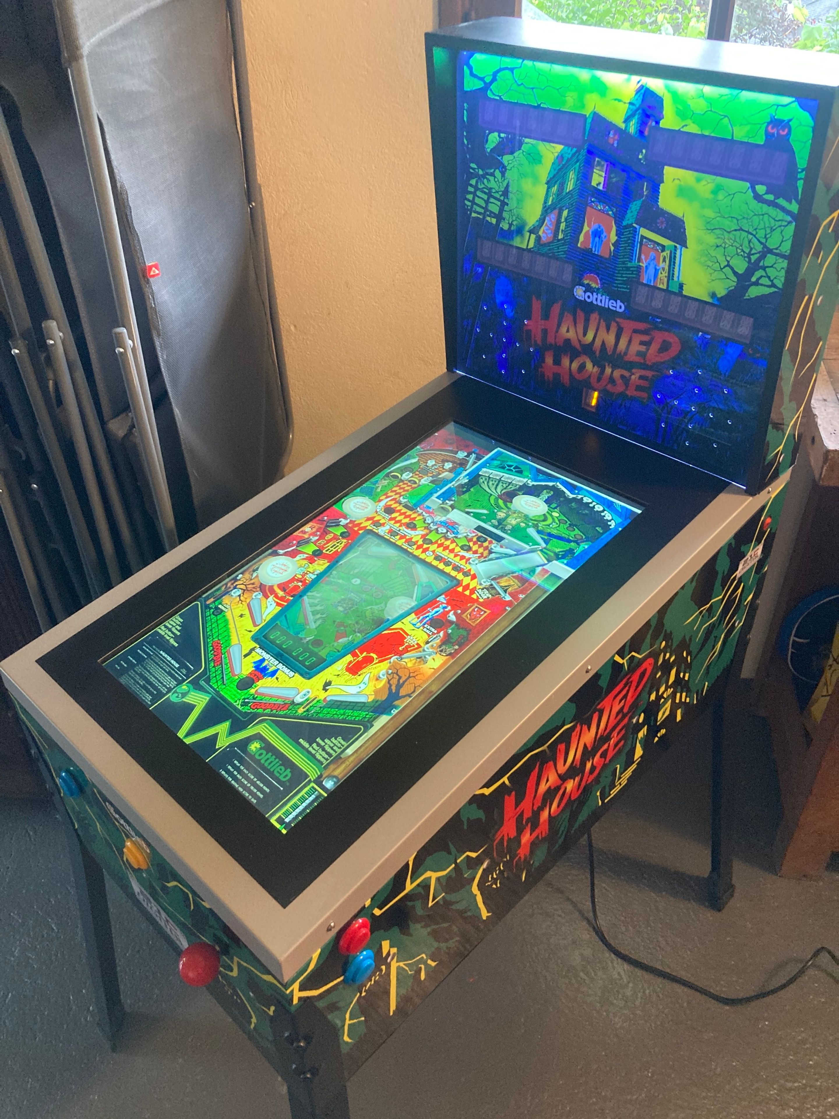 A pinball machine with a colorful playfield and the title 'Haunted House' on the screen.
