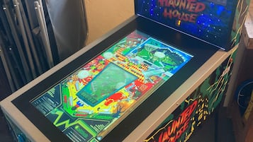 A pinball machine with a colorful playfield and the title 'Haunted House' on the screen.