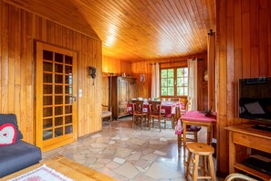A wooden interior with a dining area, a television, and a sofa.