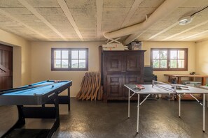 Quarto com mesa de bilhar, mesa de pingue-pongue e armário com ferramentas.