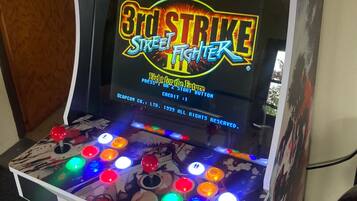 Een spelautomaat met een kleurrijke joystick en een scherm waarop het spel '3rd Strike Street Fighter' wordt getoond.