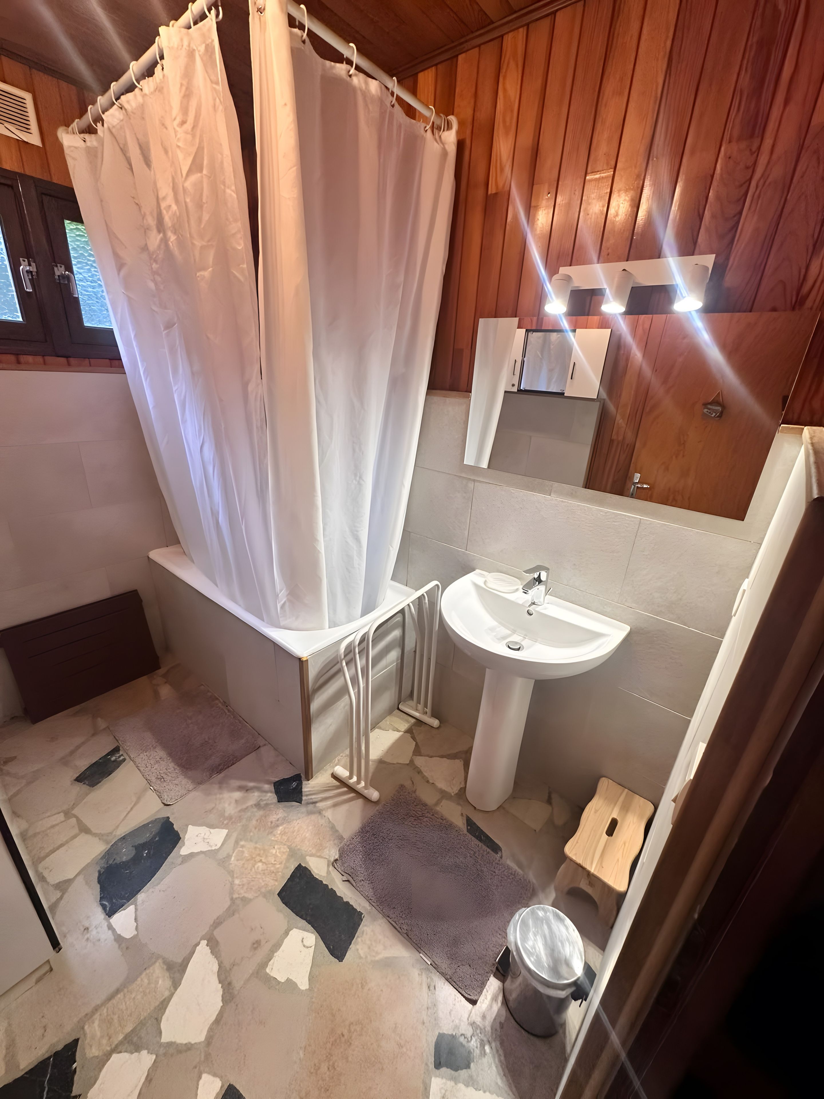 A bathroom with a shower curtain, a sink, a mirror, and a toilet.