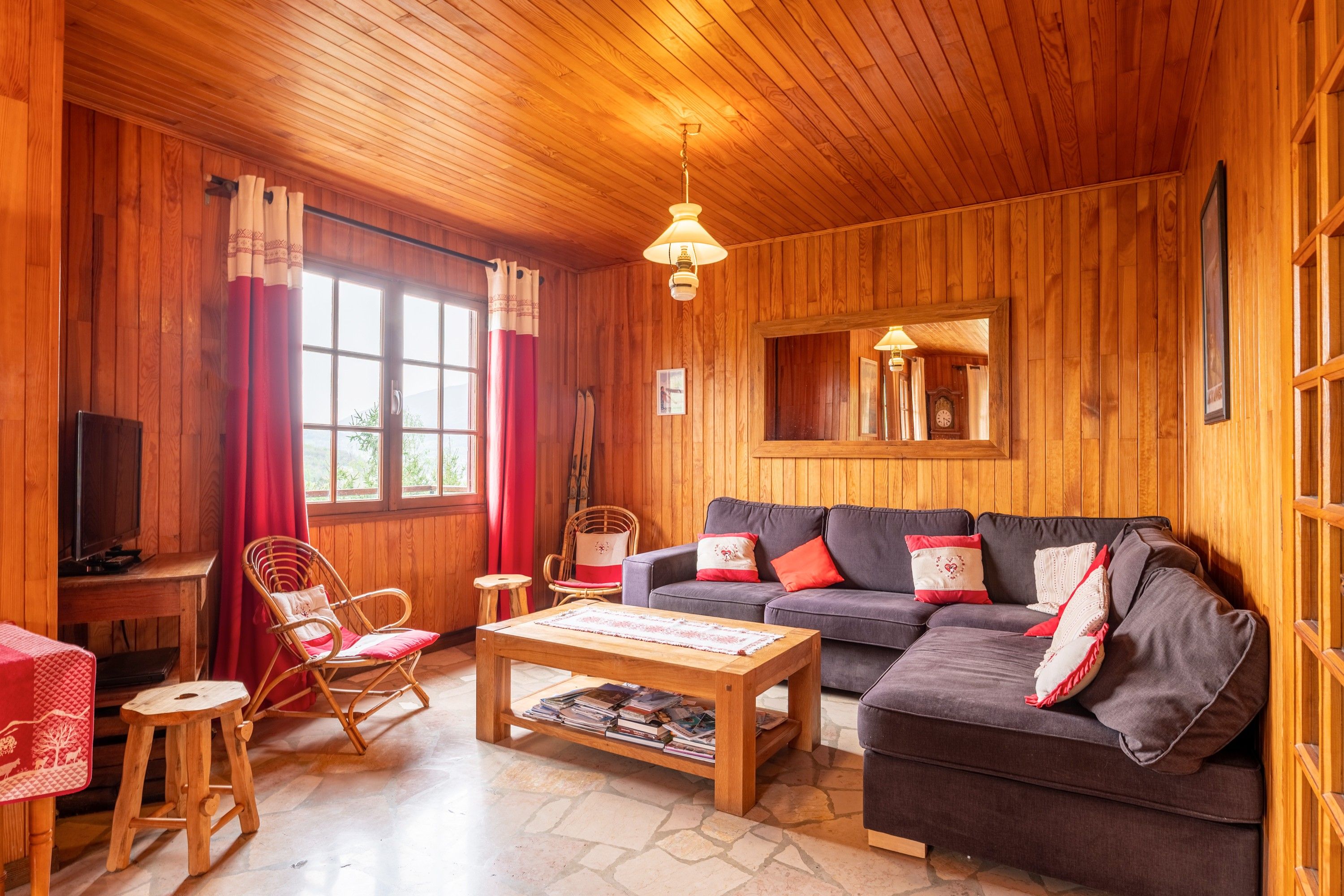 A cozy living room with wooden walls, a sofa, a coffee table, and a television.