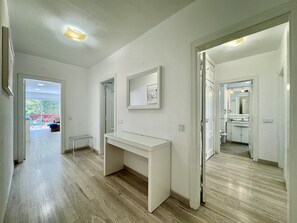 A hallway with a white console table, a door leading to a bathroom, and a view of a balcony with outdoor furniture. - VILAMOURA MARINA BEACH 2 WITH POOL by HOMING (Vilamoura)