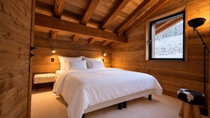 A wooden cabin bedroom with a bed, bench, and a window with a view of a snowy landscape. - NEW! Chalet Eagle - LES GETS: ski-in/ski-out, fireplace, superb view (Les Gets)