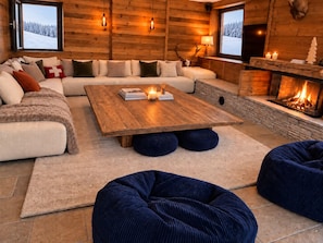 A cozy log cabin interior with a sofa, a wooden coffee table, and a fireplace. - NEW! Chalet Eagle - LES GETS: ski-in/ski-out, fireplace, superb view (Les Gets)