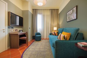 Een hotelkamer met televisie, bureau en zithoek.