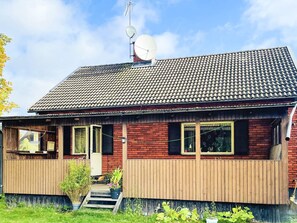 A two-story house with a tiled roof, a satellite dish, and a wooden deck. - 8 Person Holiday Home in Stockaryd (Stockaryd)