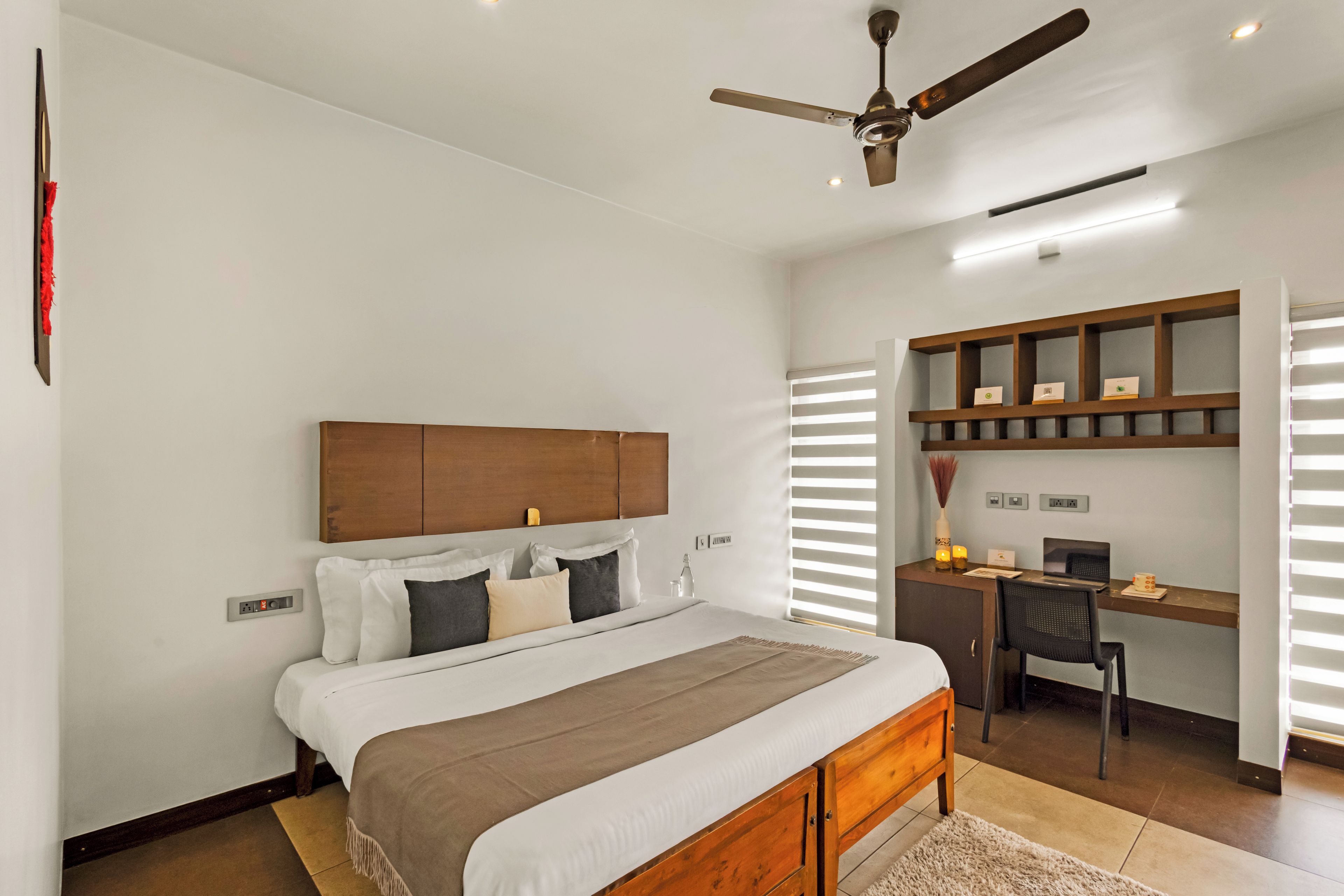 A bedroom with a bed, a desk, and a ceiling fan.