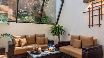 Un salón moderno con sofá, una mesa de centro y un ventanal con vistas a la vegetación.