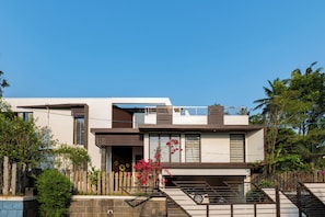 A modern two-story house with a balcony, a garage, and a staircase leading to the entrance. - Glass River Retreat (Aluva)