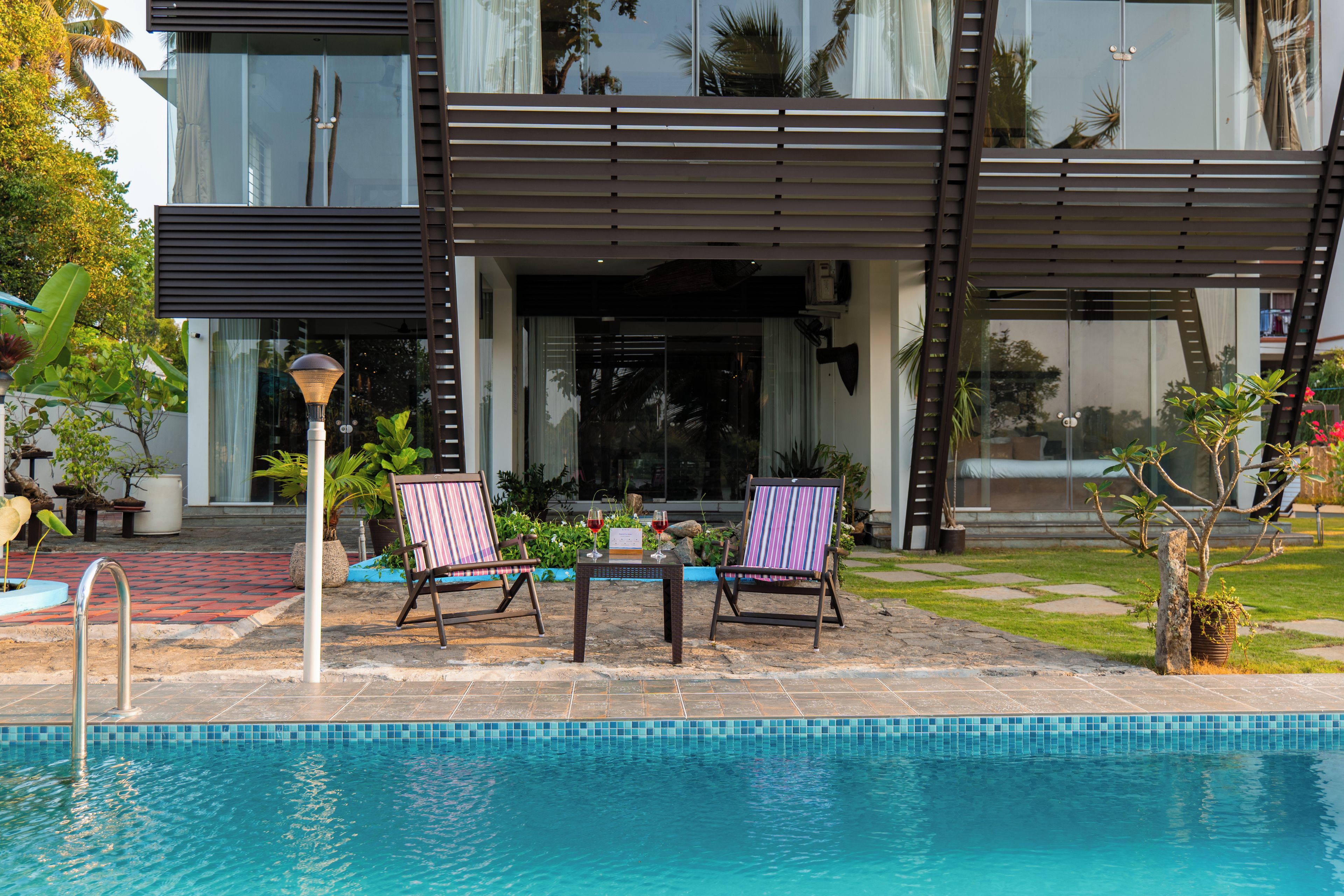 Una zona junto a la piscina con dos sillones, una mesa y una piscina.