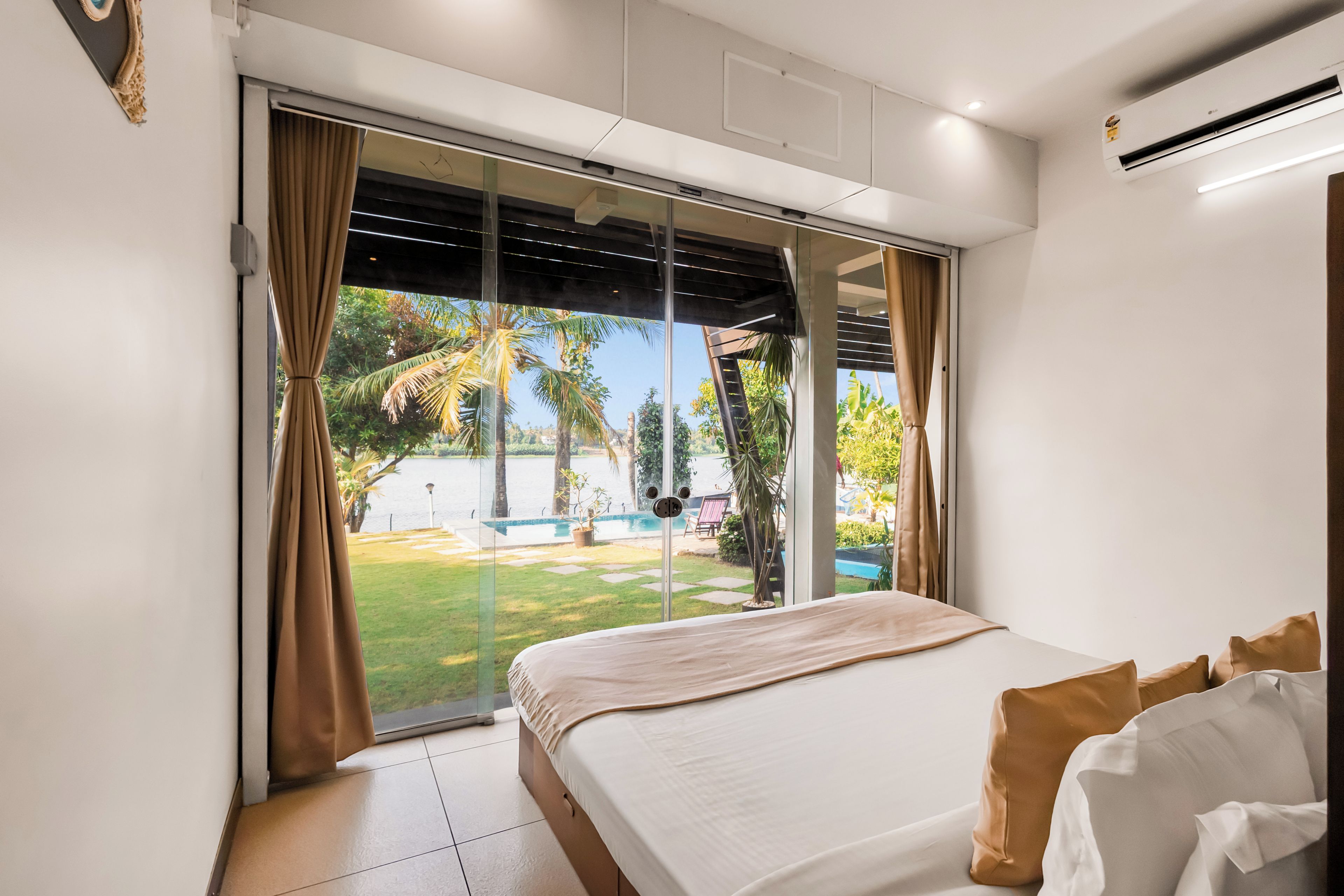 A bedroom with a bed, curtains, a window, and an air conditioning unit.