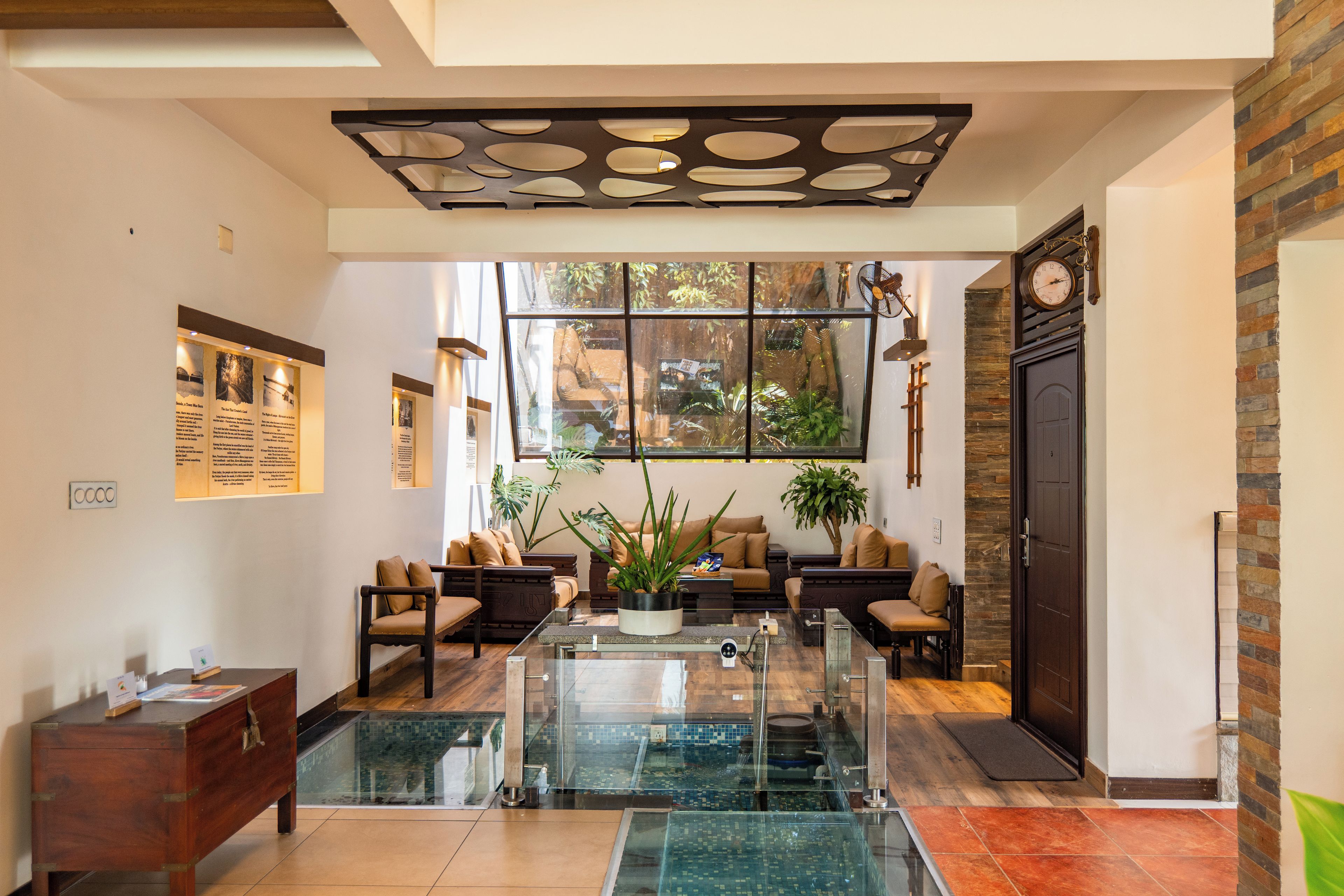 A spacious living area with a glass coffee table, comfortable seating, a large window with a view, and a stone accent wall.