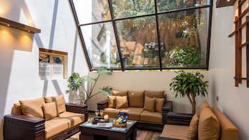 Una sala de estar moderna con un gran ventanal, muebles de madera y una pequeña mesa de centro.