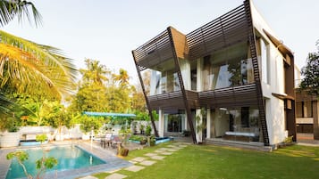 A modern house with a swimming pool, a patio, and a garden.