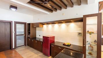 Una cocina moderna con horno empotrado, un refrigerador rojo y una vitrina de vidrio.