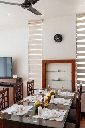 A dining area with a long table set for a meal, a clock on the wall, and a ceiling fan.