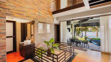 A modern interior with a stone wall, a round sink, and a view of a pool and greenery outside.