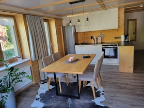 Ett modernt kök med träskåp, ett matbord med stolar och en matta av kohud.
