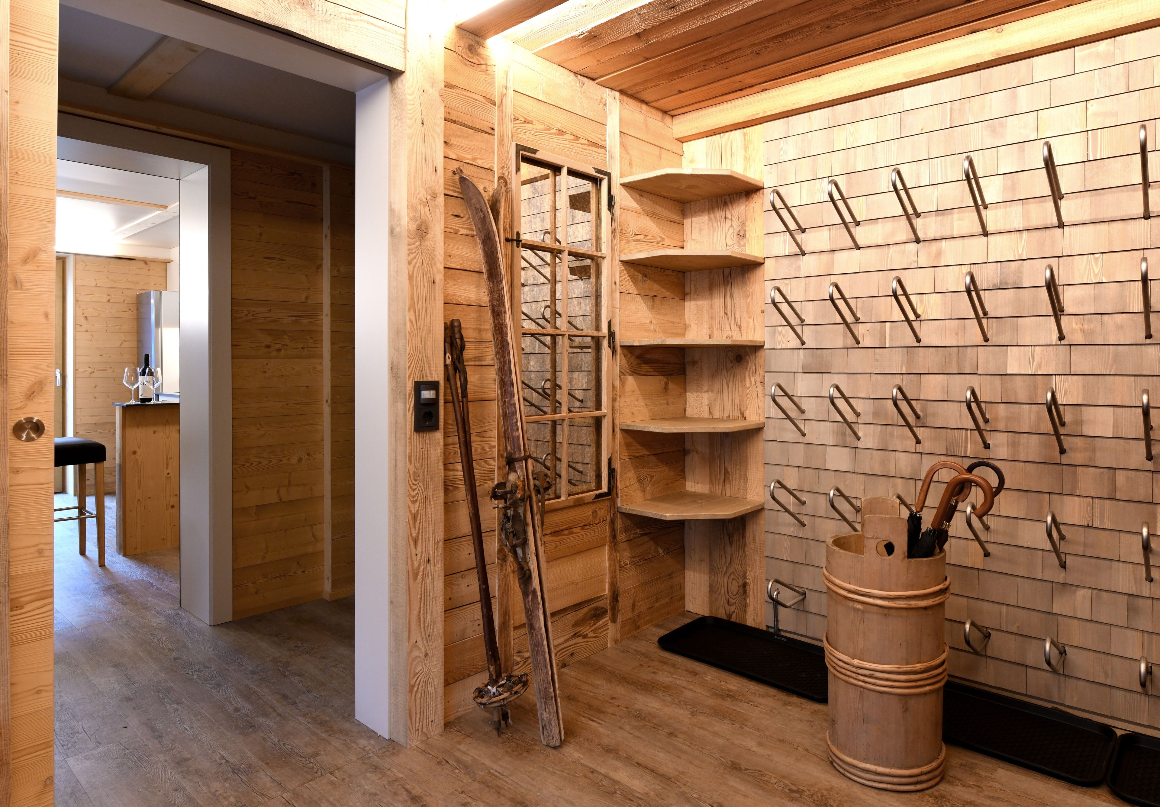 Een houten interieur met een ski-rek, een houten emmer en een bar met een kruk.