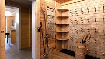 Een houten interieur met een ski-rek, een houten emmer en een bar met een kruk.