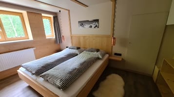 Una habitación con cama, ventana, puerta y un cuadro en la pared.